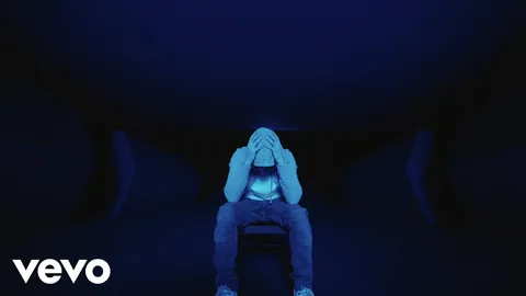 青い光の中、椅子に座り顔を伏せるEminem。「Darkness」公式MVのサムネイル。