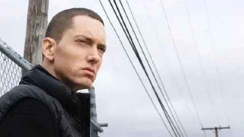 曇り空の街角で電線の向こうを見つめるEminem