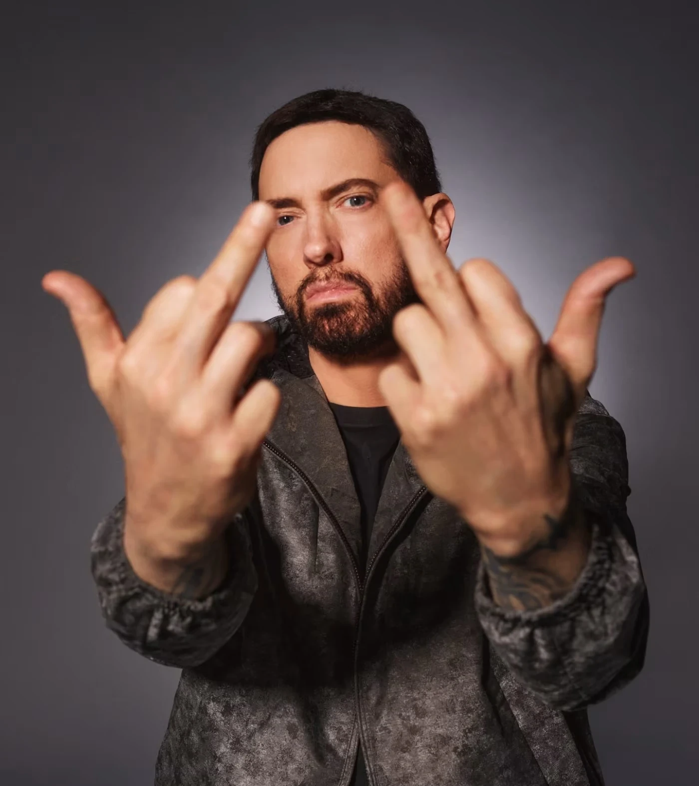グレーの背景で両手をカメラへ向けるEminem